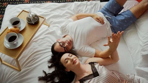 Romantic couple lay on bed, hold hands, have breakfast at morning Stock Footage 125433470