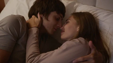 Romantic Couple Lying Face to Face on Pillow, Kissing and Cuddling Tenderly 스톡 동영상 323259545