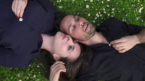 Romantic couple lying on the lawn talking amiably Stock Footage 73035985