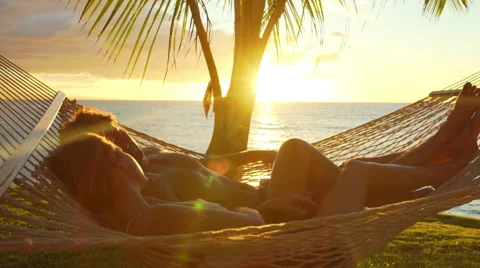 Romantic couple relaxing in tropical hammock at sunset. Summer Luxury Vacation Stock Footage