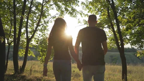 Romantic couple in a romantic summer evening holding hands goes on sunset Stock Footage 124902304