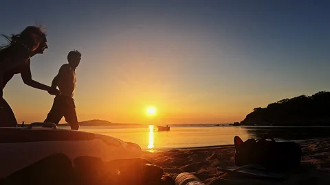 Romantic Couple Running Into Frame Hugging And Kissing On Beach At Sunset Video stock 335699157