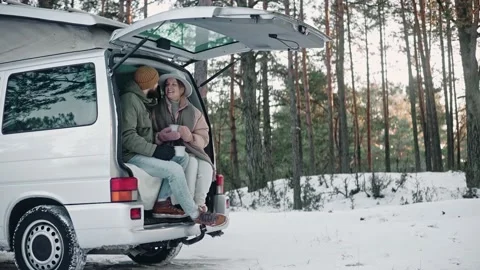 Romantic couple sitting at the back of a van in the woods on a sunny winter day 스톡 동영상 169504346