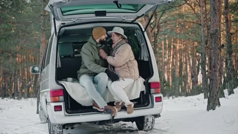 Romantic couple sitting at the back of van in the woods on a sunny winter day Stock Footage 169505690