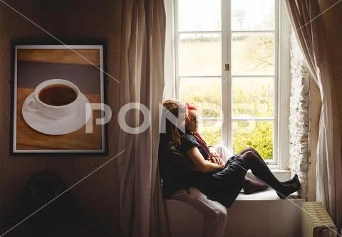 Romantic couple sitting together on window sill at home PSD Template