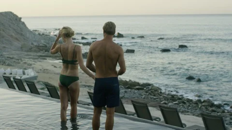 Romantic couple standing in infinity pool at dusk Stock Footage 106330497