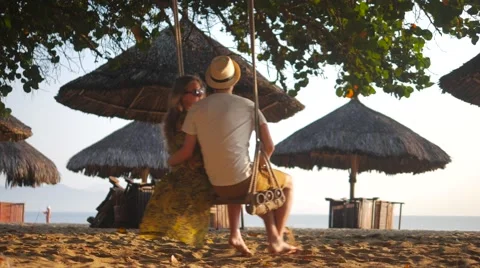 Romantic couple swinging under the tree at a beach and talking to each other Stock-Footage 62602366