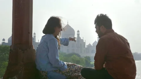 A romantic couple talking and sitting outdoors against the Taj Mahal Video stock 138732798