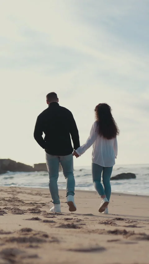 Romantic couple walking on sandy beach at sunset Stock Footage 327186636