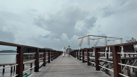 A romantic couple walking together along a wooden pier over the water Video stock 343395948
