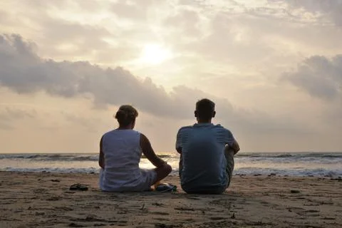 A romantic couple watching the sunset on a beach Stock Photos