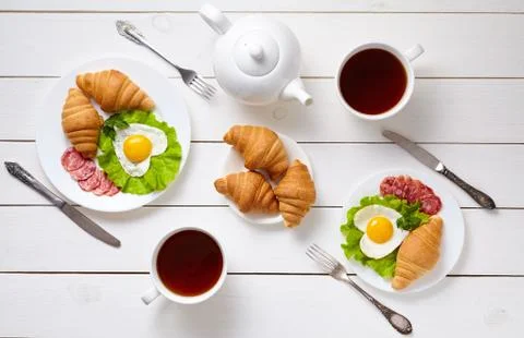 Romantic creative breakfast for two with heart shaped eggs, salad, croissants Stock Photos