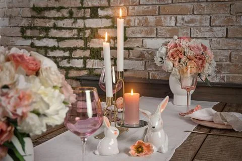 Romantic cute table decor with glasses flowers and lit candles. Wedding easte Stock Photos