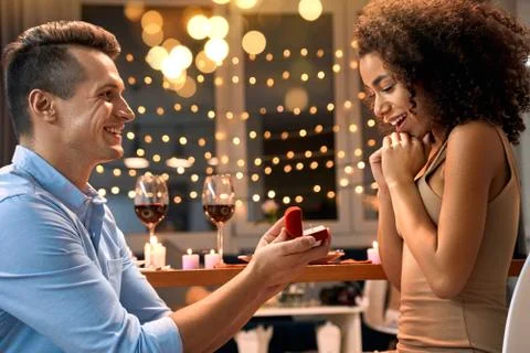 Romantic Date. Young multiethnic couple at home having dinner man standing on Stock Photos