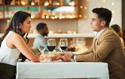 Romantic dates are their thing. an affectionate young couple holding hands while Stock Photos