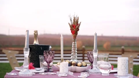 The romantic decor of a table arranged in the middle of nature with candles Stock Footage 155385058