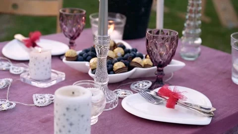 Romantic decor, a table on the green meadow decorated with tall golden candles Stock Footage 155935416