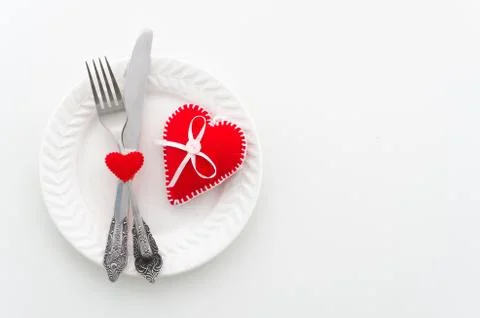 Romantic dinner concept. Ceramic plate with cutlery and felt hearts. Top view Stock Photos