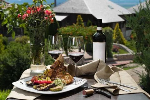 Romantic dinner outside. an appetizing dish of pork ribs and two glasses of red Stock Photos