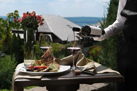 Romantic dinner outside. an appetizing dish of pork ribs and two glasses of red Stock Photos