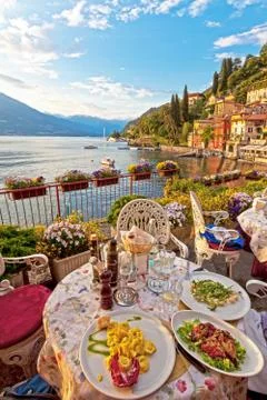 Romantic dinner scene of plated Italian food on terrace overlooking lake Stock Photos