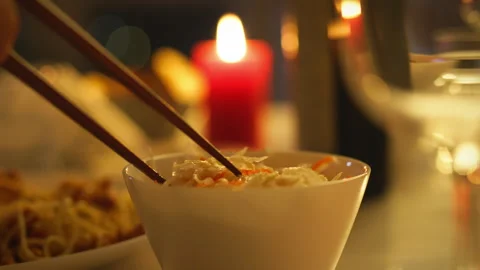 Romantic dinner setting with chopsticks and candlelight enhances dining expe Stock Footage 301407324