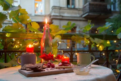 Romantic dinner table on balcony with candles, chocolates and fruits Stock Photos