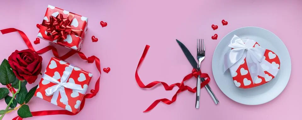 Romantic dinner table. Gift or present box, red rose, mini heart, plate, fork Stock Photos