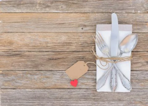 Romantic dinner table setting with silver cutlery, red heart shape and tag Stock Photos