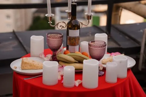 Romantic dinner table setting with wine bottle glasses and white candles on.. Stock Photos