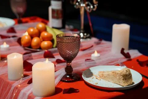 Romantic Dinner Table Setup with Candles, Wine Glass, Cake Slice, and Rose .. 스톡 사진