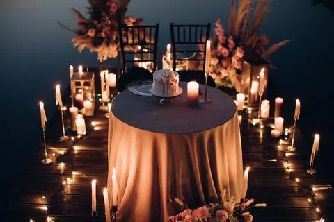 Romantic dinner for two by candlelight on the beach in the evening Stock Photos