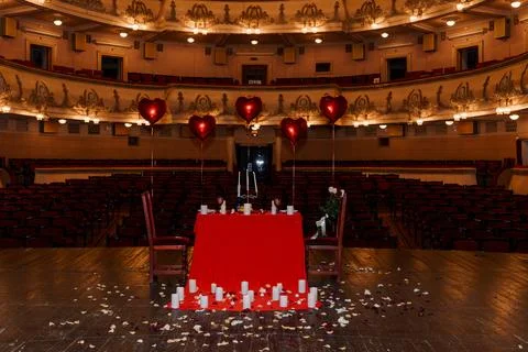 Romantic dinner for two with red tablecloth and heart balloons on a theater.. Stock Photos