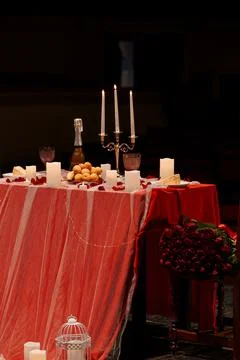 Romantic dinner for two with red tablecloth, candles, champagne, and red ro.. Stock Photos
