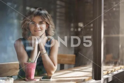 Romantic dreamy millennial blond curly-haired nice girl sit alone cafe table Stock Photos