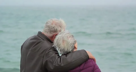 Romantic elderly couple hugging on beach on a cold windy day Video stock 318183144