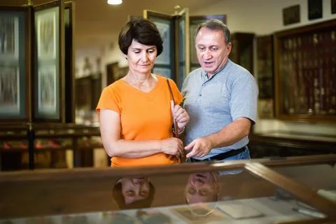 Romantic elderly couple interested in objects of applied arts in museum Fotos Stock