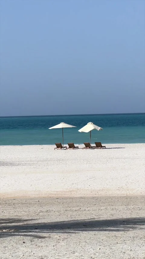 Romantic escape featuring beach beds beneath beach umbrella set against Stock Footage 282182633