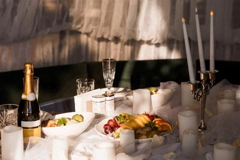 Romantic evening dinner setting with sparkling wine, fresh fruit, and glowing 스톡 사진