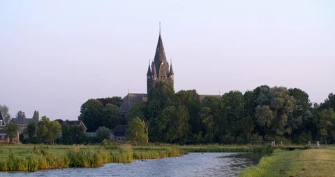 Romantic evening landscape with river, meadows and church tower, Netherlands 4K Stock Footage 91582873