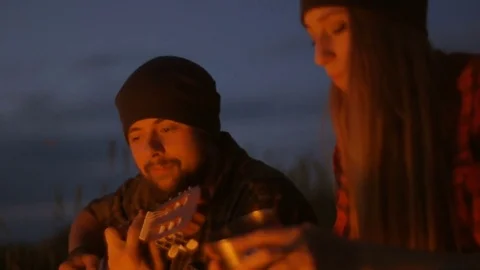 Romantic evening near the fire. Two young lovers sitting on the night before the Видео 76045694