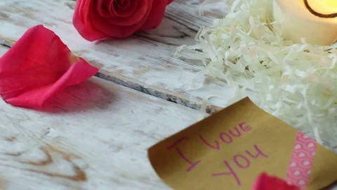 Romantic Interior, Valentine's day table. Rose, gift card, candle, 4k pan shot Video stock 71361599