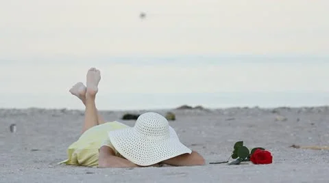 Romantic lady laying down on beach sand near a red rose Stock-Footage 12272396
