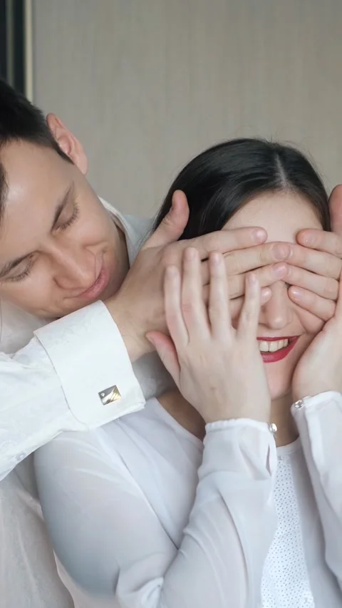 Romantic man surprising his girlfriend by covering her eyes with his hands for a Stock Footage 343909821