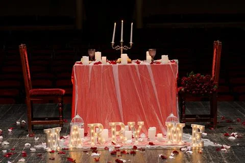 Romantic marriage proposal dinner table with glowing letters and red roses .. Stock Photos