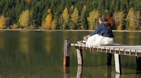 Romantic modern girl sitting on the mountain lake pontoon and thinking Stock Footage