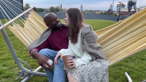Romantic multiethnic couple with coffee in cup talk and smile while sitting Stock Footage 252449879