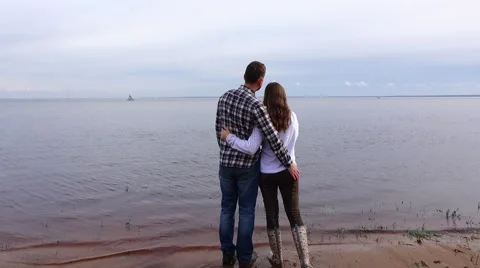 Romantic pair stand on lake coast, kiss and hug, look at distance Stock Footage