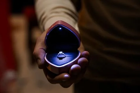 Romantic Proposal Moment with Diamond Ring in Heart-Shaped Box Held by Hand.. Stock Photos