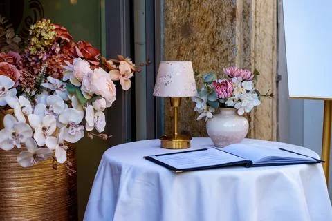 Romantic Restaurant Table Setting with Flowers and Open Menu Book Stock Photos